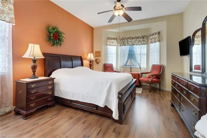 Bedroom with wood-type flooring, multiple windows, and ceiling fan