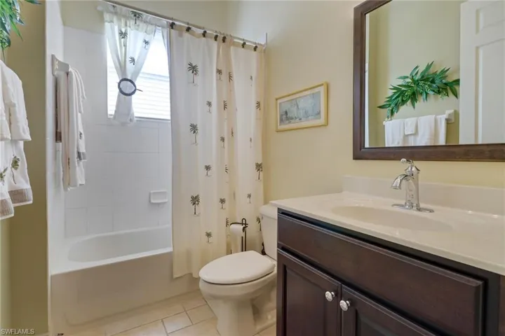 Full bathroom with tile patterned floors, vanity, shower / bath combination with curtain, and toilet