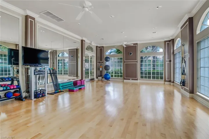 Exercise area featuring light hardwood / wood-style flooring, ceiling fan, and ornamental molding