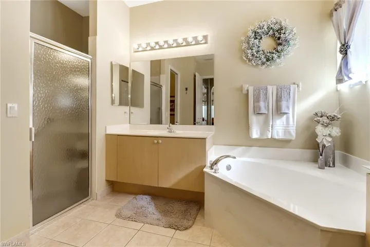 Bathroom featuring plus walk in shower, vanity, and tile patterned flooring