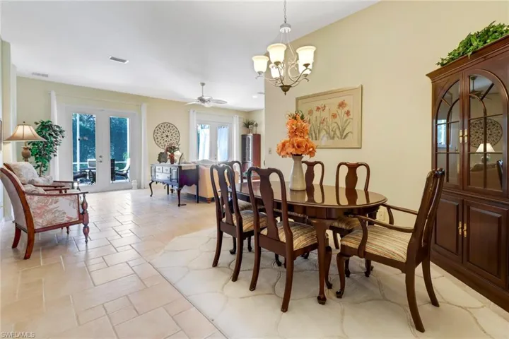 Dining space with french doors and ceiling fan with notable chandelier