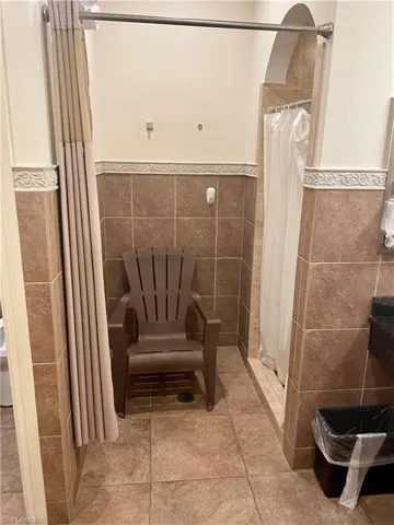 Bathroom featuring tiled shower, a wainscoted wall, and tile walls
