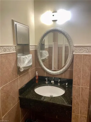 Bathroom featuring vanity, wainscoting, and tile walls