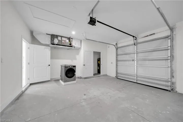 Spacious garage featuring a concrete floor, overhead garage door, built-in air handler, and a side access door