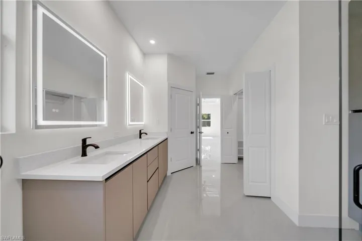 Master bathroom with dual vanity and rectangular undermount sinks, light-toned countertop, and matte black faucets