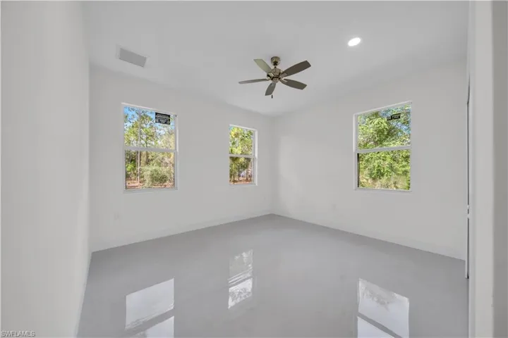 guest bedroom number two featuring three windows, a ceiling fan with integrated lighting, recessed lighting, and light-toned tile flooring