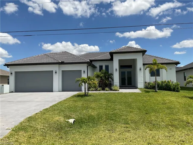 The property features a well-maintained lawn, a concrete driveway leading to a two-car garage, and an inviting entryway