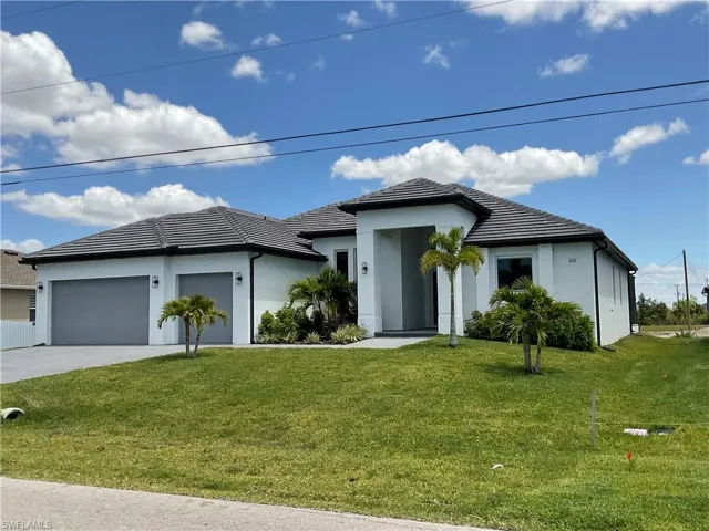 The property features a white exterior, a dark tiled roof, and a well-maintained green lawn