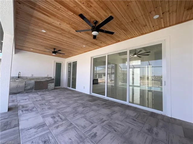 Expansive outdoor living area featuring a wooden ceiling with recessed lighting and ceiling fans, tiled flooring, and sliding glass doors