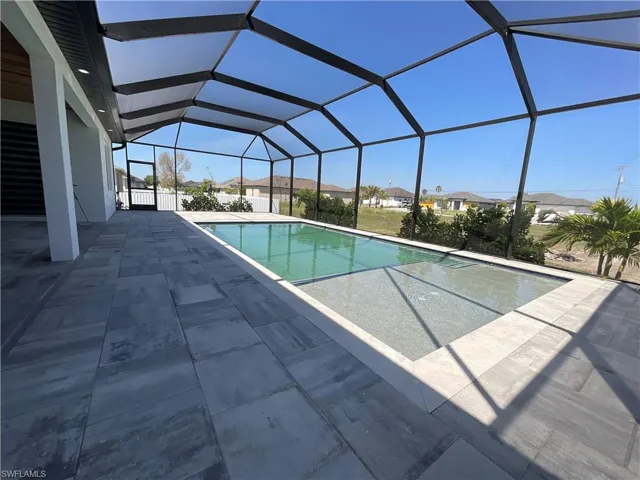 This property features an expansive screened lanai with a swimming pool, complemented by a spacious patio laid with large format tiles