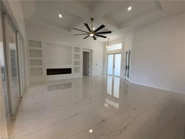 This expansive living area features large format tile flooring, a modern linear fireplace, and built-in shelving