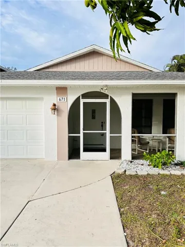 View of front facade with roof with shingles, a sunroom, an attached garage, and stucco siding