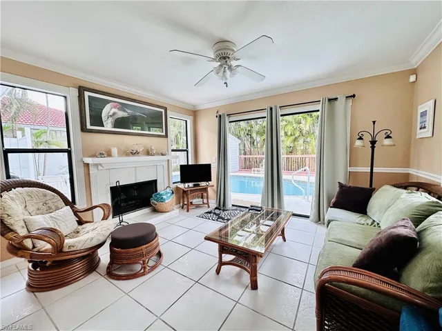 Tiled living room featuring crown molding, a tiled fireplace, and ceiling fan