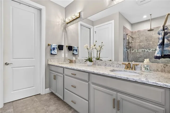 Full bath featuring double vanity and a tile shower