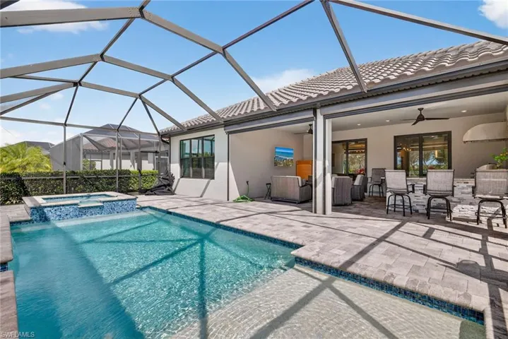 Relaxing pool / spa with a patio, a sunroom, a lanai, and a bar