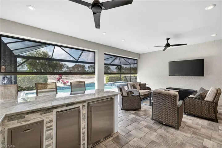 View of patio / terrace featuring exterior kitchen, a ceiling fan, a pool with connected hot tub, and a lanai