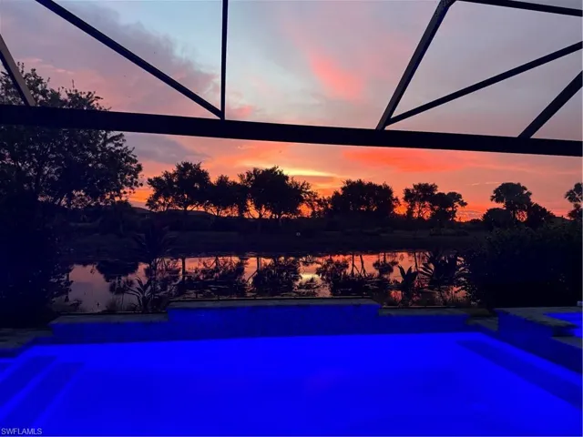 Pool at dusk with a patio and a water view