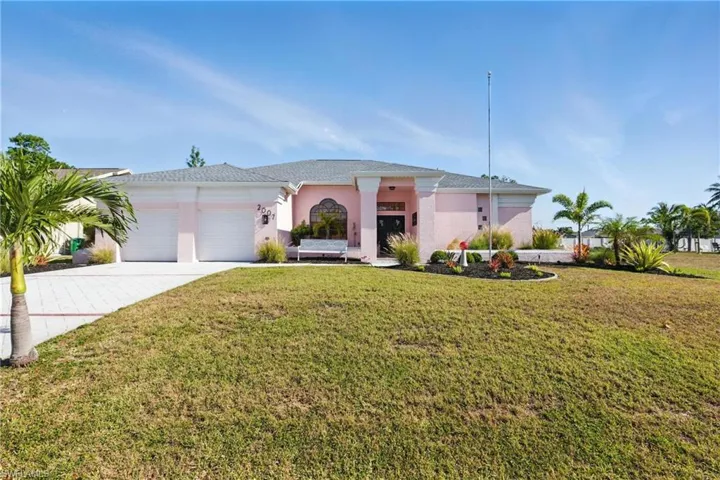 View of front of house with a front yard, driveway, stucco siding, and an attached garage