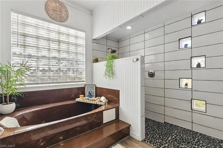 Full bath with a bath, wood finished floors, crown molding, and walk in shower