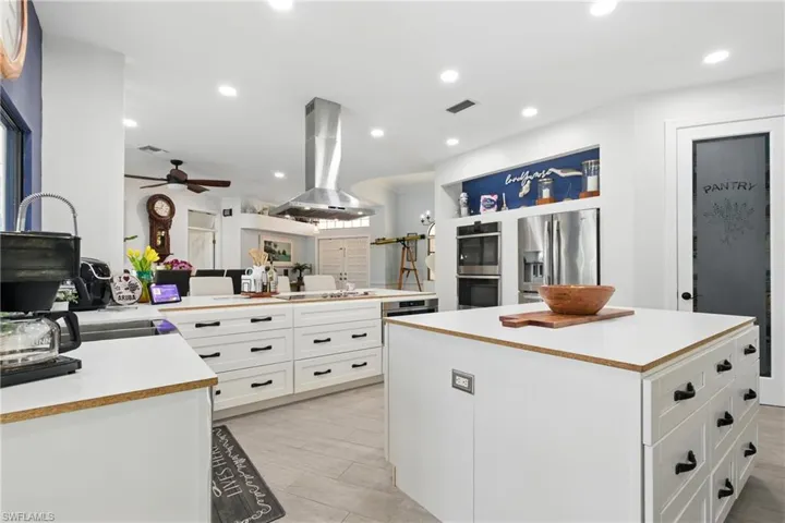 Kitchen featuring visible vents, light countertops, a ceiling fan, island exhaust hood, and stainless steel appliances