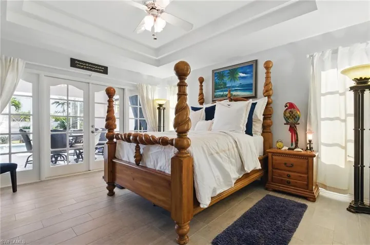 Bedroom with a tray ceiling, access to outside, and ceiling fan