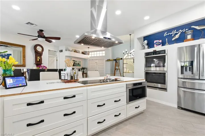 Kitchen featuring visible vents, white cabinets, exhaust hood, light countertops, and appliances with stainless steel finishes