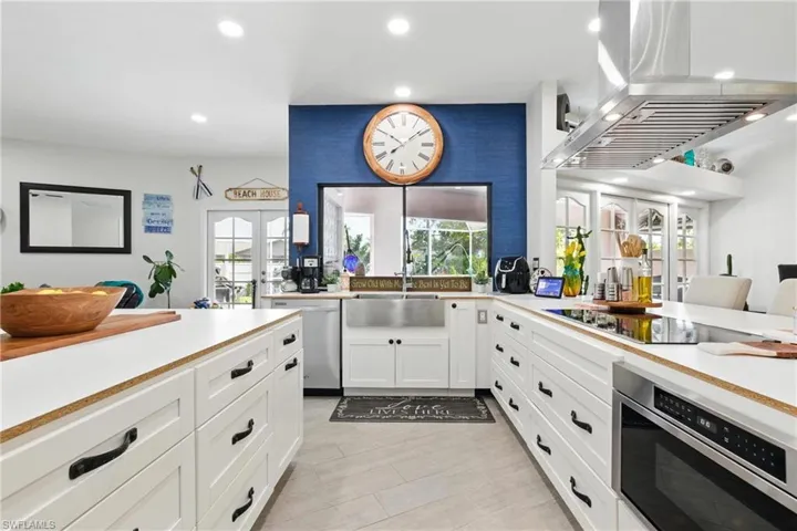 Kitchen with white cabinets, recessed lighting, appliances with stainless steel finishes, island exhaust hood, and a sink