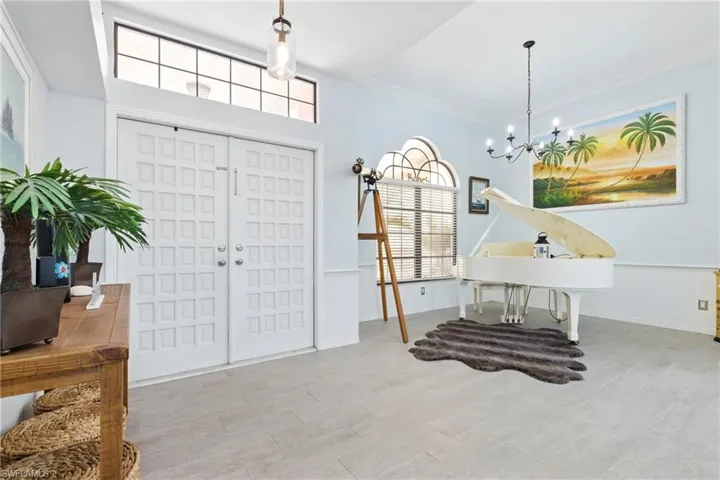 Entryway with crown molding, wood finished floors, a notable chandelier, and a wainscoted wall