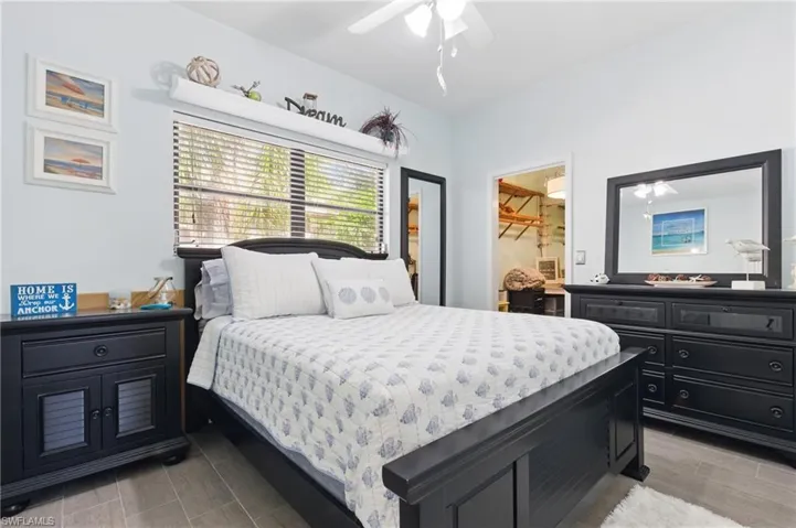 Bedroom with a walk in closet, a ceiling fan, and wood finished floors