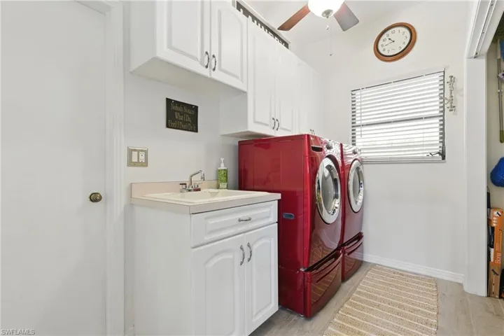 Clothes washing area with ceiling fan, washing machine and clothes dryer, a sink, baseboards, and cabinet space