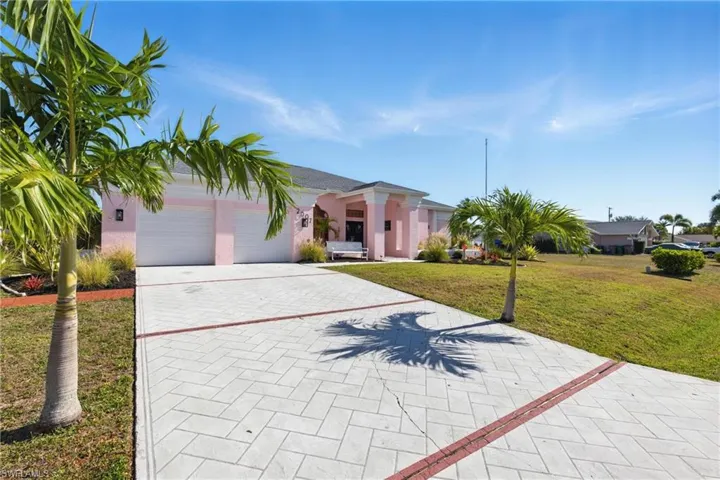 View of front of house with a front yard, a garage, driveway, and stucco siding