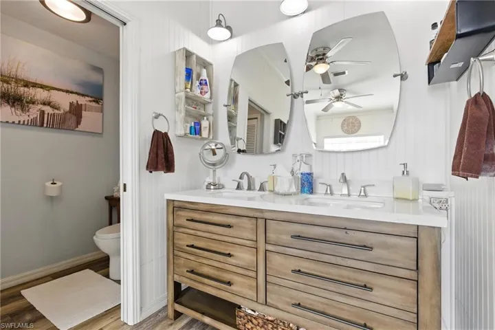 Full bath with double vanity, a sink, toilet, and ceiling fan