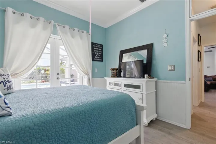 Bedroom with baseboards, crown molding, a wainscoted wall, access to exterior, and wood finished floors