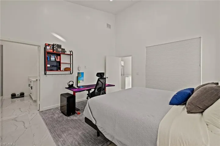 Bedroom featuring a high ceiling and light marble finish flooring