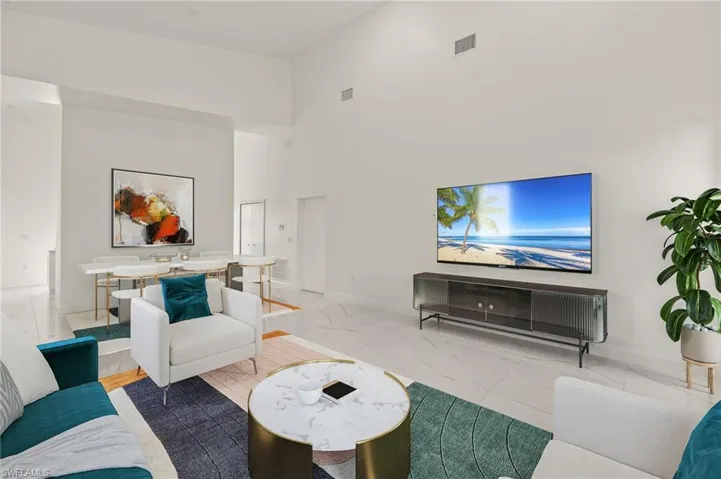 Living area featuring a high ceiling and baseboards