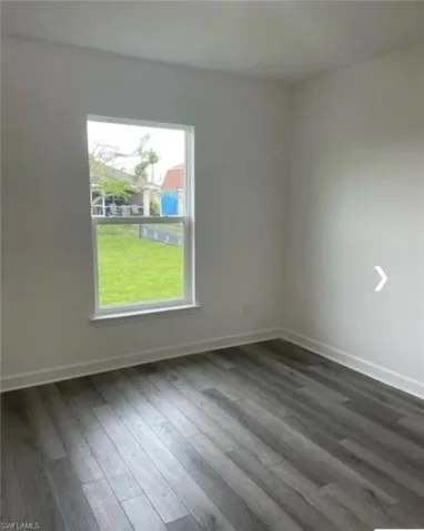 Spare room with dark wood finished floors and baseboards