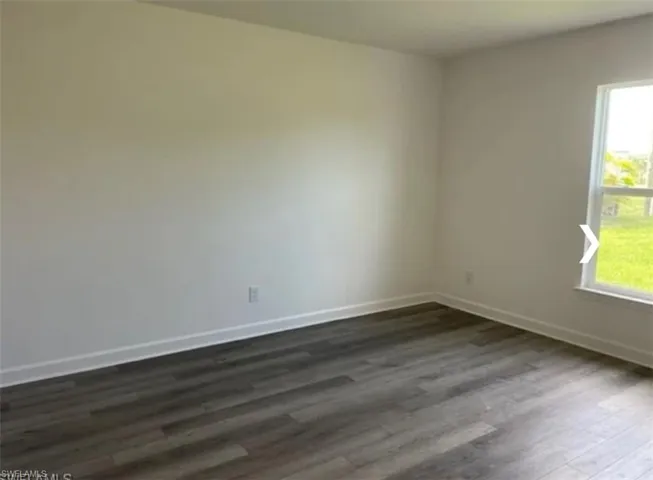 Unfurnished room featuring dark wood finished floors and baseboards