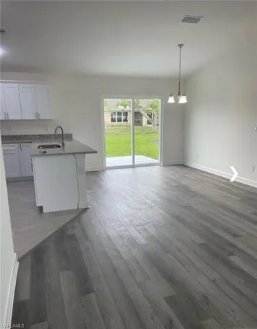 Unfurnished dining area with dark wood-style floors and a chandelier