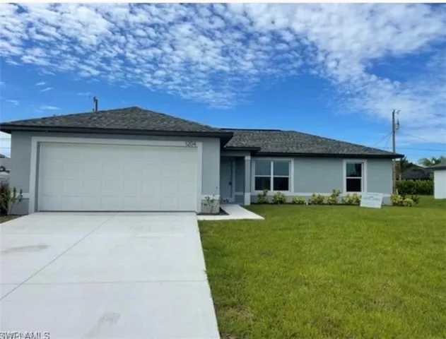 Ranch-style home with stucco siding, a front yard, an attached garage, and concrete driveway