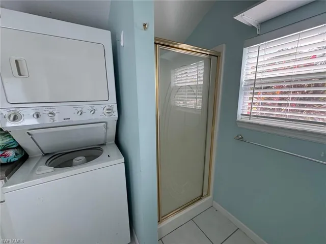 Laundry area featuring light tile patterned flooring and stacked washer / dryer