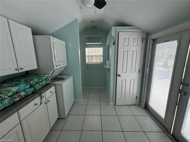 Laundry room with stacked washing maching and dryer, a healthy amount of sunlight, ceiling fan, and light tile patterned floors