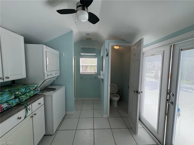 Clothes washing area featuring ceiling fan, light tile patterned flooring, and stacked washer / drying machine