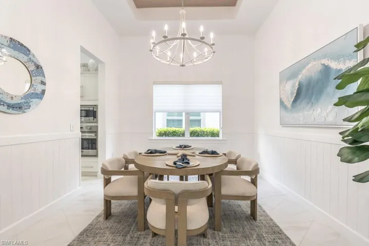 Coastal inflences make this dining room special, with custom shiplap and wood plank tray ceiling and new bright modern chandelier perfectly sized for the room