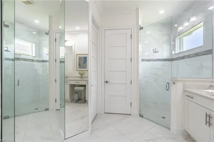 Large walk-in shower has outdoor light through a high window, rainhead shower, built-in bench and floor to ceiling tile.