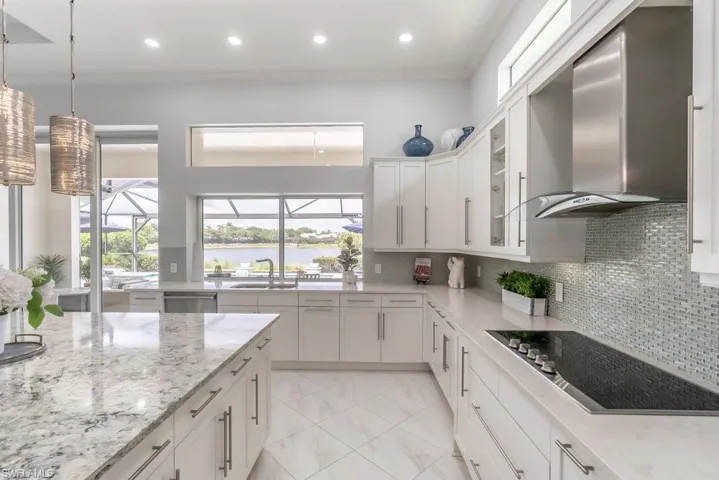High ceilings and three large windows bring in natural light to the kitchen...not to mention the pocket sliders above the sink!Beautiful seaglass tiled backsplash is highlighted by under cabinet lighting