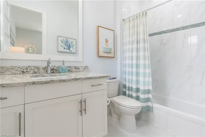 An adjoining charming bathroom has a tub and shower, beautiful granite top vanity and large mirror.
