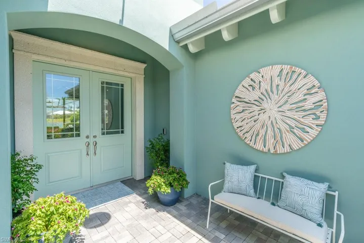 Pristine entryway anchored by trees and planter with colorful flowers