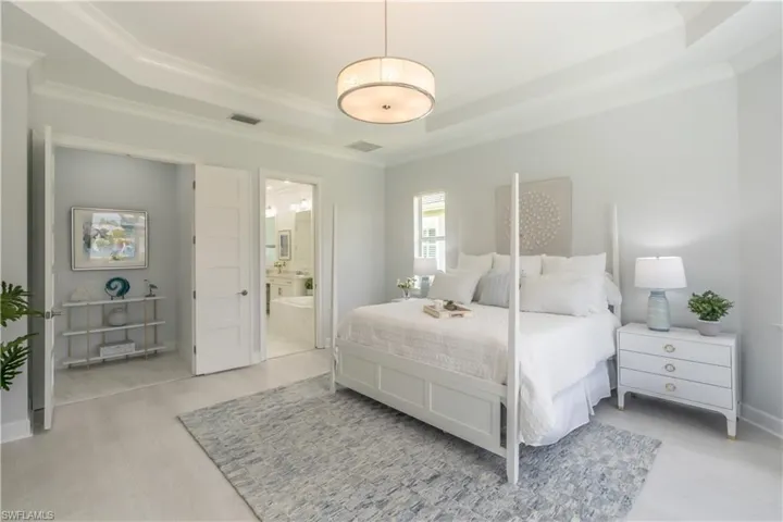 The spacious primary bedroom suite has a high tray ceiling, crown molding and designer chandelier. All doors in the house are modern solid 8 ft 6 panel doors.