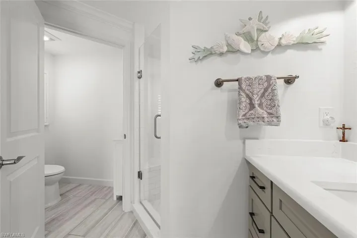 Full bathroom with baseboards, toilet, a shower stall, and vanity