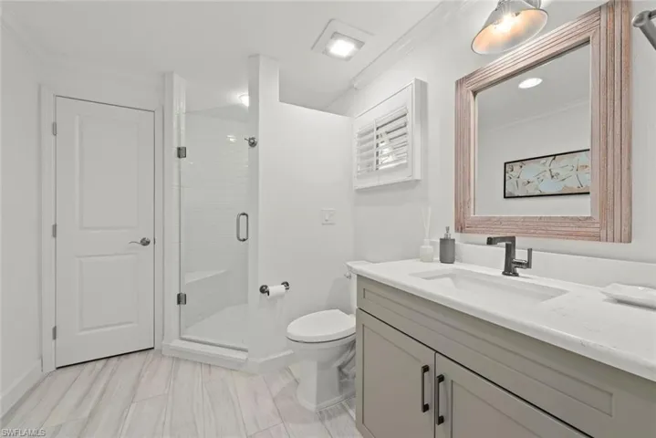 Full bath with toilet, vanity, baseboards, a shower stall, and crown molding